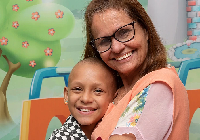 Paciente Infantil com Cancêr sendo cuidado por uma voluntária - IncaVoluntario - INCA